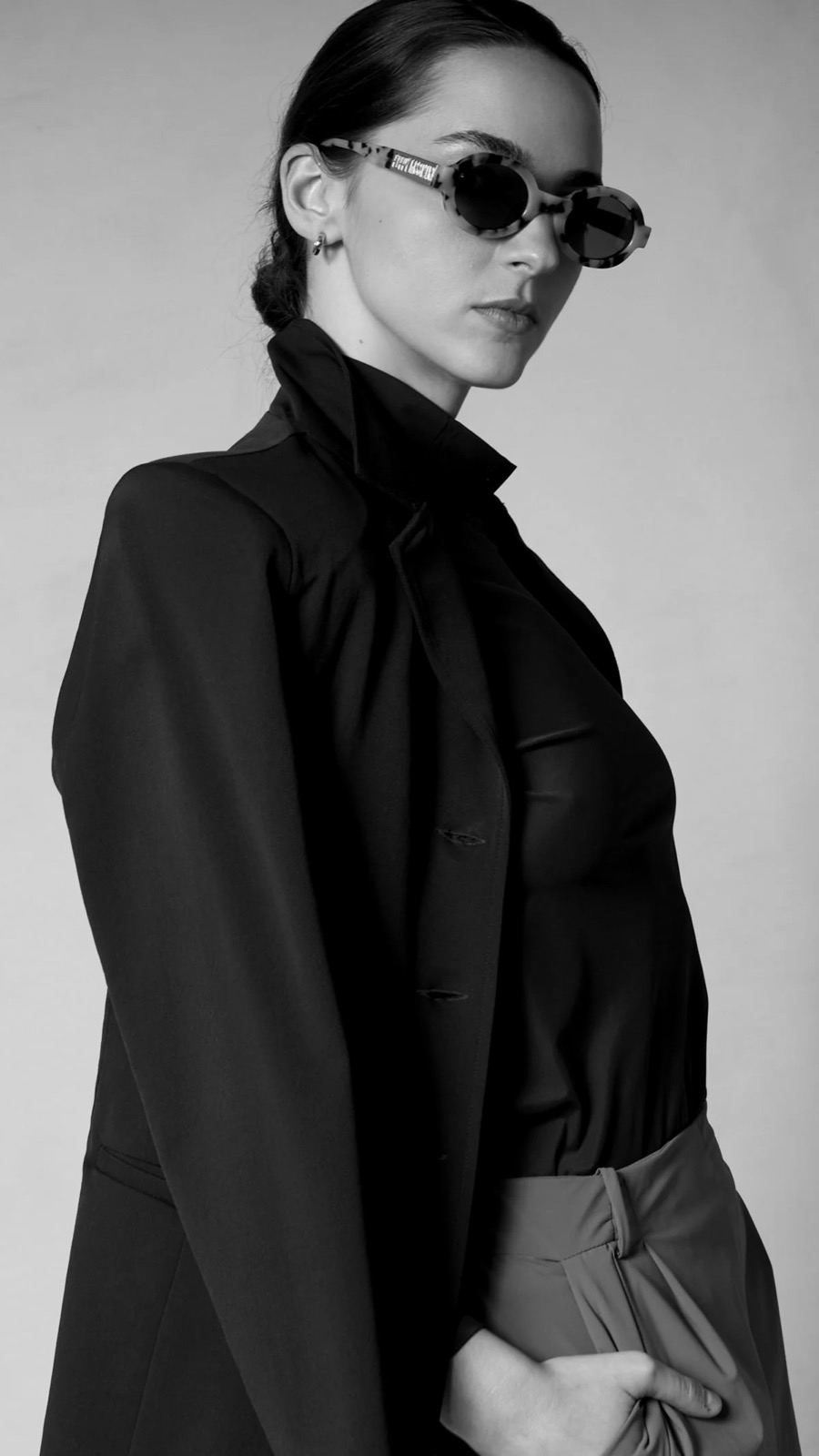 A model in a tailored black CALLIDAE jacket and sunglasses