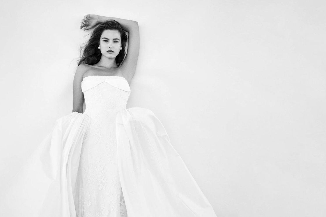 A bride in a strapless Houghton gown posed against a white wall